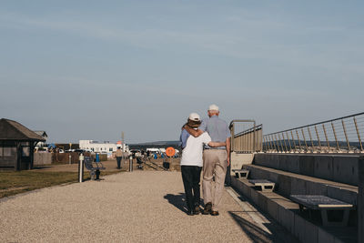 Man standing on railing against sky