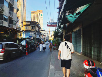 Rear view of people walking on city street