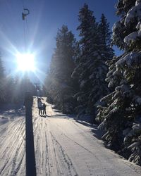 People walking on snow covered road against sky