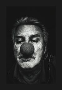 Close-up of man wearing clowns nose against black background