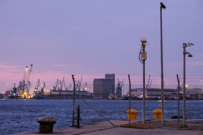Illuminated street light by sea against clear sky