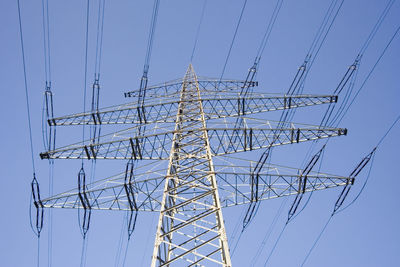 Low angle view of electricity pylon against clear blue sky