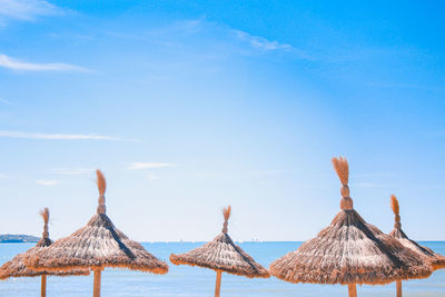 Traditional windmill on beach against blue sky