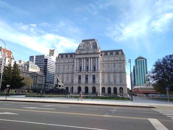 Road by buildings against sky in city