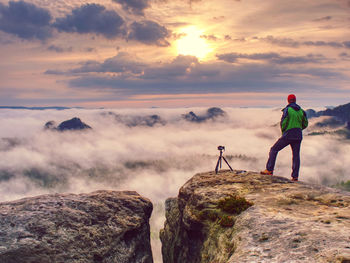 Photographer or videographer traveler close to tripod with digital camera prepared for an art work