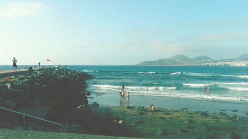 People on beach against clear sky