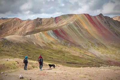 Rear view of people walking on mountain against sky