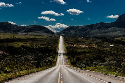 Road leading towards mountains against sky