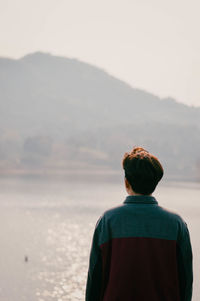 Rear view of man looking at sea against sky