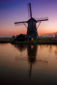 Traditional windmill on field during sunset