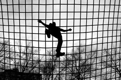 Low angle view of silhouette boy playing against sky