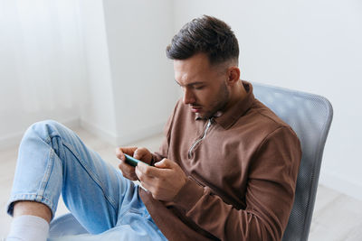 Young man using mobile phone while sitting on sofa at home