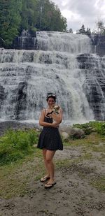 Portrait of smiling woman standing against waterfall