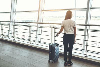 Rear view of woman standing at airport terminal