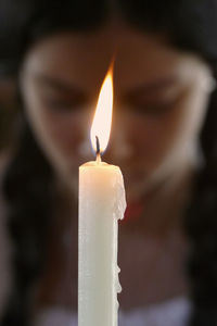 Close-up of illuminated candle with woman