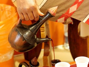 Cropped image of person pouring coffee in traditional container