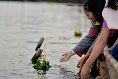 Side view of young woman putting incense with flower on lake