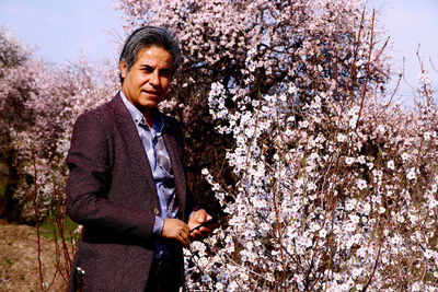 Portrait of man standing by cherry blossom