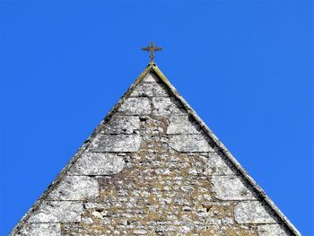 Low angle view of cross on building against clear blue sky