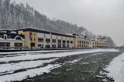 Snow covered railroad tracks by buildings against sky