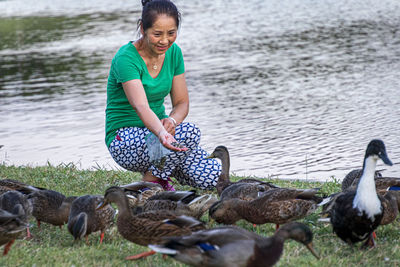 Senior woman feeding birds against lake