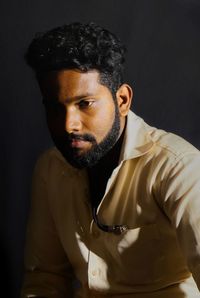 Bearded man looking away against black background