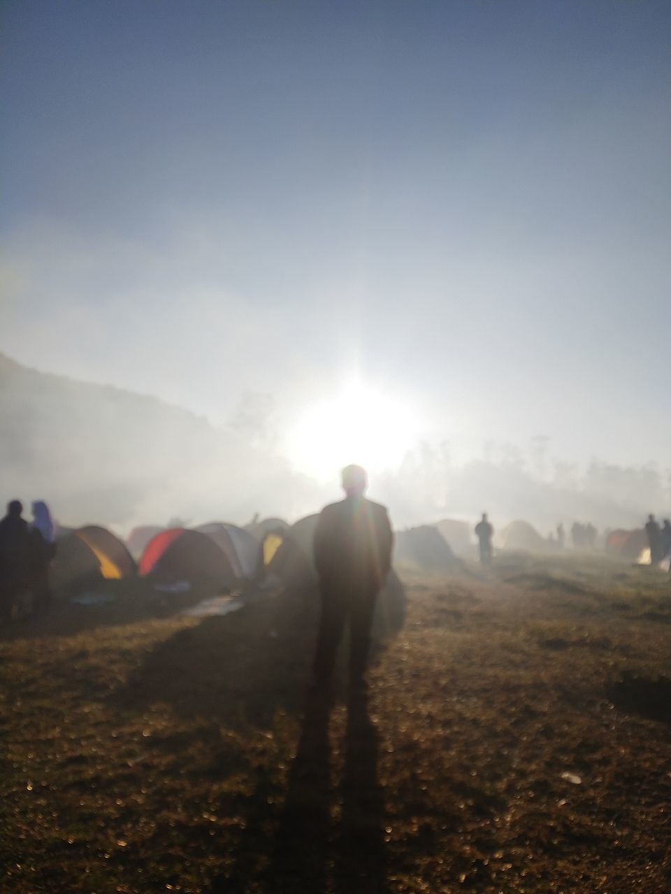 PEOPLE WALKING ON FIELD AGAINST SKY DURING SUNRISE