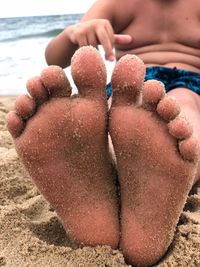 Midsection of woman relaxing on sand at beach