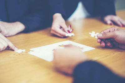 Business colleagues holding jigsaw pieces at desk in office