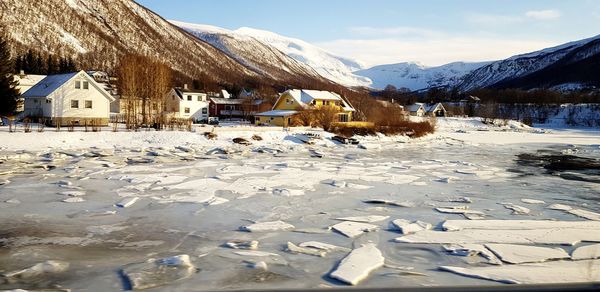 Snow covered houses by buildings against sky