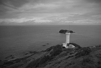 Lighthouse by sea against sky