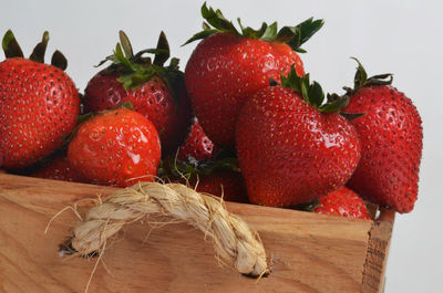 Close-up of fresh red strawberries in wooden box against white background