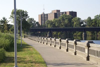 Footpath by buildings in city against clear sky