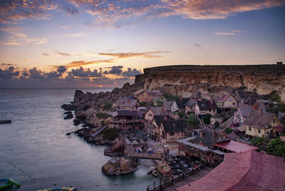 High angle view of townscape by sea during sunset