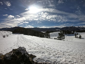 Scenic view of snow covered landscape against bright sun