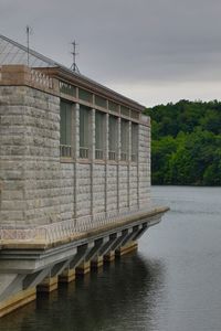 Built structure by river against sky