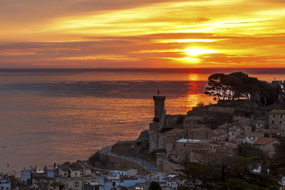 High angle view of townscape by sea against sky during sunset