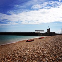 Scenic view of beach against cloudy sky