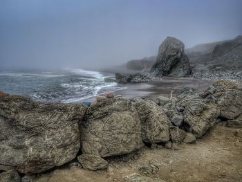 Rocks in sea against clear sky for man napping 