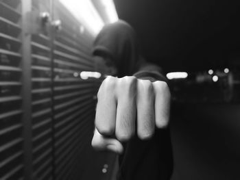 Close-up of man with clenching fist at night