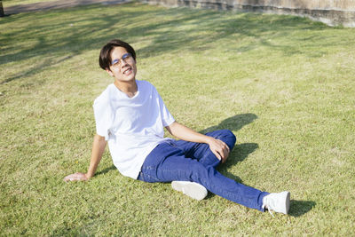 Full length of smiling young ma sitting on grass