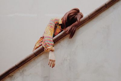 Low angle view of woman leaning on railing against white wall