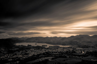 Aerial view of city and mountains against sky at sunset