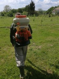 Rear view of woman photographing on field