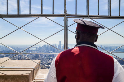 Rear view of man standing at window in empire state building