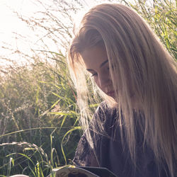 Beautiful woman with long blond hair while reading book on grassy field
