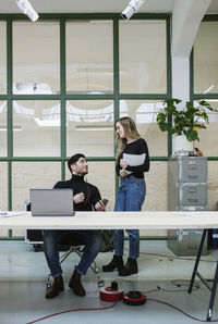Two colleagues talking at desk in office