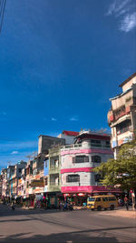 City street by buildings against blue sky