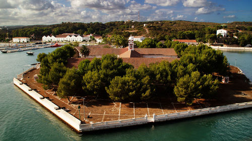 High angle view of buildings amidst trees in sea against sky