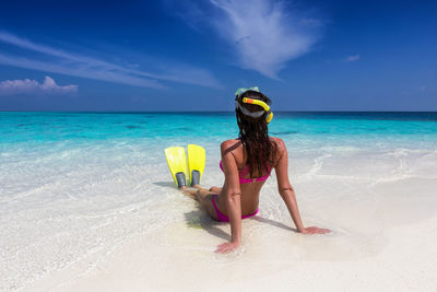 Woman relaxing at beach against blue sky